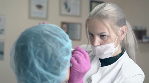 Blonde Woman Makes Brow Tattooing on Client Face in Clinic
