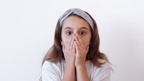 Young Girl Covering Mouth with Hands in Surprise