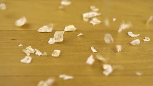 Rolled Oats Falling onto a Wooden Surface