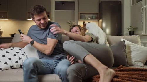 Couple playfully fight for TV remote at home