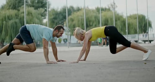 Side View of Fit Man and Woman in Sportswear Smiling and Doing Mountain Climber Exercise During