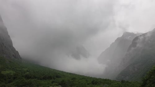 Misty Clouds Swirl Through Mountainous Valley