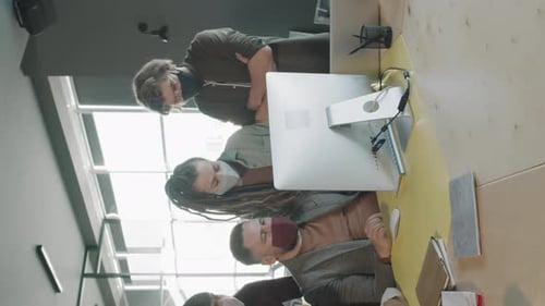 Foto vertical da equipe de empresários trabalhando com máscaras faciais