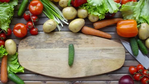 Top View of Chef Hands Rolling Fresh Cucumber on Cutting Board