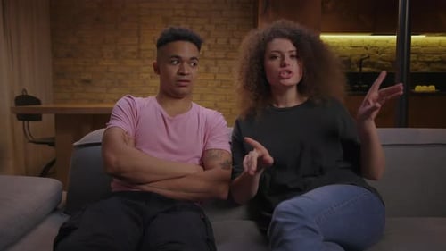 Young Wife Complaining About African American Husband Talking To Psychotherapist Looking at Camera