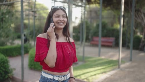 a Cute Brunette Girl Makes a Phone Call in a City Park