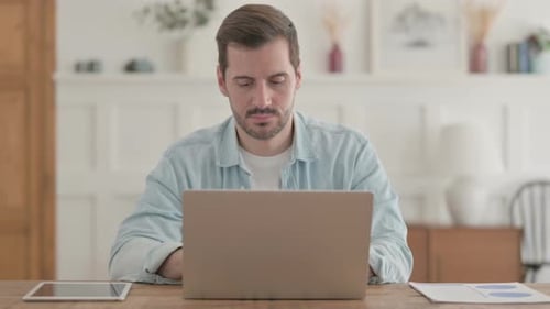Young Man Working on Laptop in Office