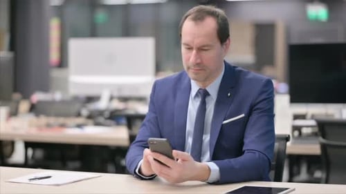 Attractive Businessman Using Smartphone in Office