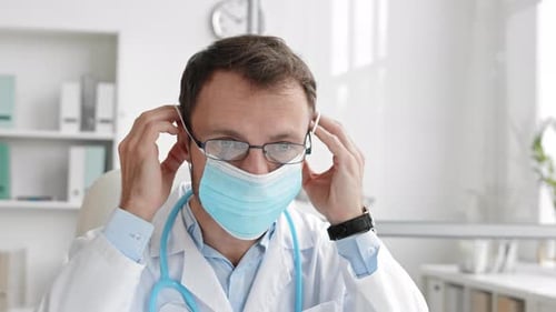 Doctor Puts on a Surgical Mask in Office