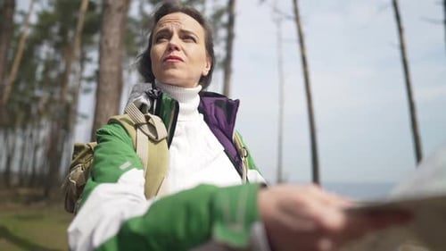 Portrait of Worried Beautiful Female Tourist with Paper Map Standing in Forest Looking Around