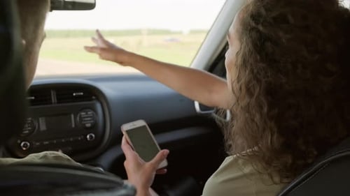Woman Passenger Points Out Window While Holding Cellphone