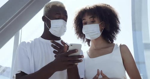 Woman and Man Looking at Cellphone with Masks
