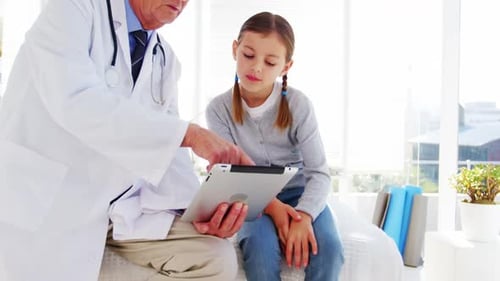 Doctor Showing Digital Tablet to Young Girl