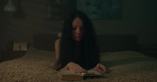 Girl Reading a Book on Bed at Night