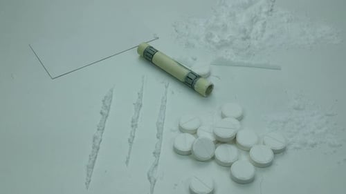 White Powder, Pills, and Money on White Background
