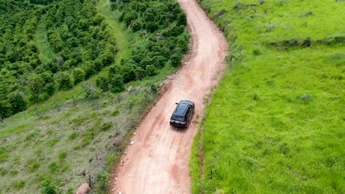 Aerial View of Car Driving Throuh a Small Dirt Road in the Middle of Green Tropical Valley