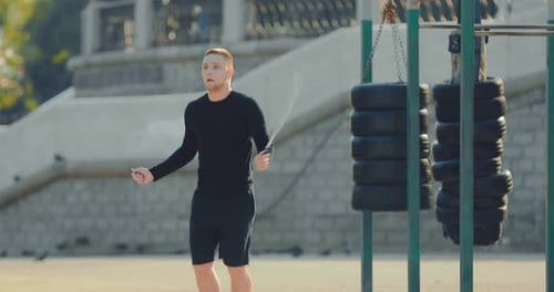 Young Guy is Professionally Jumping Rope Warming Up in the Summer on the Sports Field