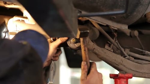 Mechanic Repairing Undercarriage of Car with Tools