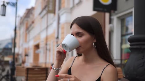 Young beautiful girl sitting at table In cafe with cup of coffee or chea In hands.