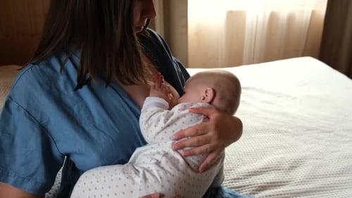 Woman Breastfeeding Infant in Natural Light at Home