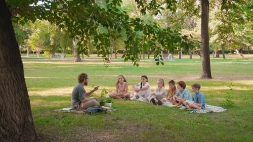 Teacher Explaining Nature to Young Students in Park