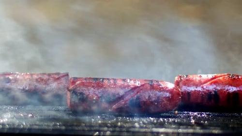 Sizzling Sausages Cooking on a Grill with Smoke