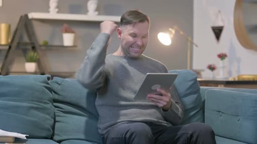 Excited Man Celebrates Good News on Tablet