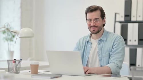 Man Working at Laptop Gives Thumbs Up