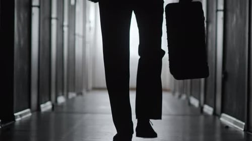 Silhouette of Person Walking in Corridor with Briefcase