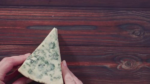 Hands Displaying a Triangle Piece of Blue Cheese