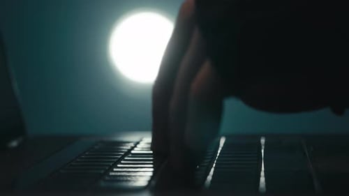 Hacker Typing on Keyboard in the Night