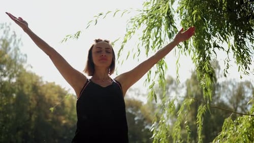 The Girl Performs Warmup Exercises Before Yoga in Nature n Park