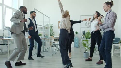 Diverse Professionals Celebrate Dancing in Modern Office