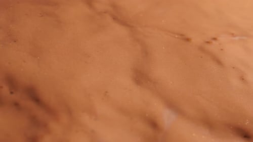 Textured Brown Liquid Flowing in Close-up