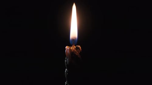 A Single Candle Is Lit on a Black Background. Candle Flame in the Dark.