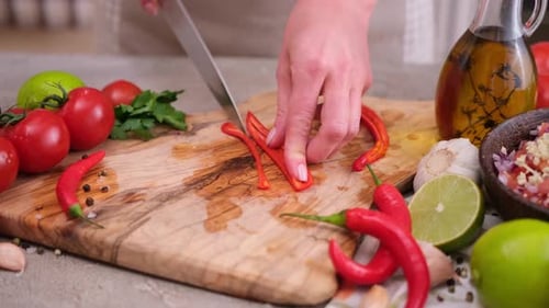 Person cutting a red pepper on cutting board