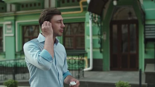 Man Walking and Using Wireless Earbuds in City