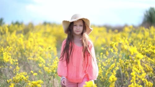 Young Girl Walks in a Rapeseed Field.