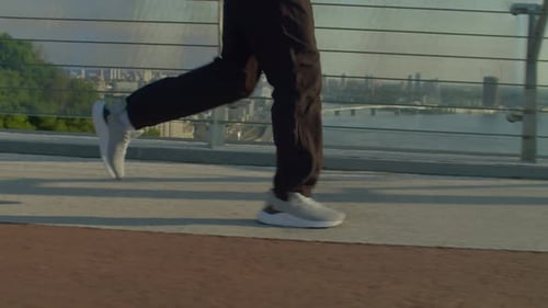 Side View of Motivated Sporty Fit Man Practicing Morning Jog in City at Dawn