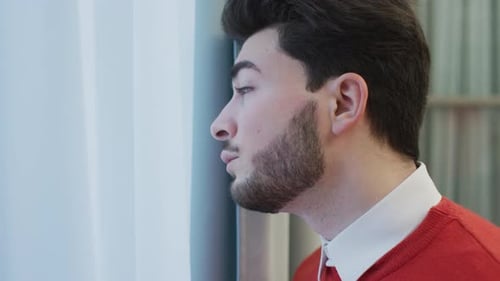 Man Looks Out Window with Thoughtful Expression
