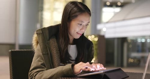Woman use of tablet computer in coffee shop at night