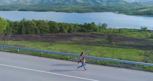 Junge Freundinnen genießen morgens einen Lauf in der Nähe des malerischen Sees