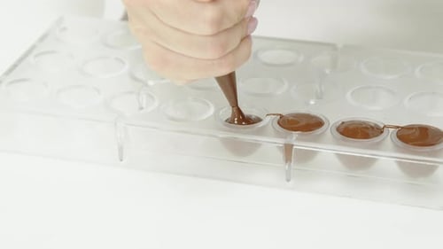 Close-up Chocolatier Squeezing Dark Cream for Chocolate Candies with Pastry Bag