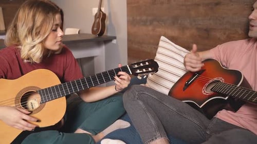 Man and Woman Play Guitars Together at Home