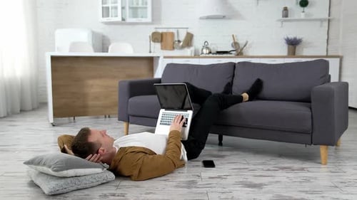 Adult Works on Laptop While Relaxing on Floor