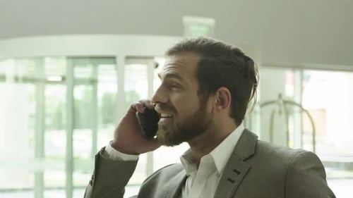 Bearded Businessman Chatting on Phone in Modern Building