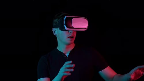 Young Man in VR Glasses. A Man Immersed in Virtual Reality Makes Movements with His Hands