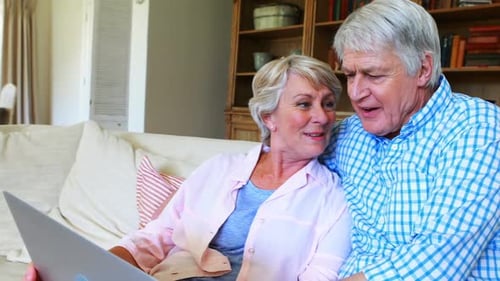 Senior Couple Using Laptop at Home on Couch