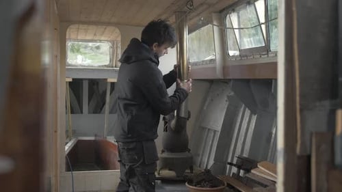 Man Installs Pipe on Wood Burning Stove on Boat