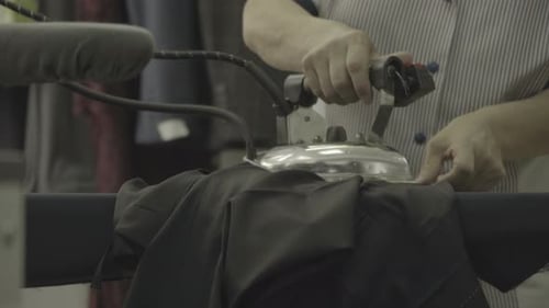 Hands of a seamstress ironing pants